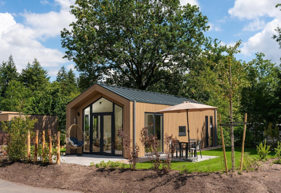Modern Tiny Lodge with terrace and parasol at Veluwepark de Bosgraaf in the Netherlands, surrounded by nature.