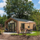 Moderne Tiny Lodge med terrasse og parasol ved Veluwepark de Bosgraaf i Holland omgivet af natur.