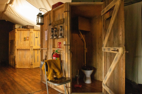 Rustikale Holzhütte mit Vintage-Toilette und Laternen im Feather Down Hoeve de Betuwe Ferienpark, Gelderland.