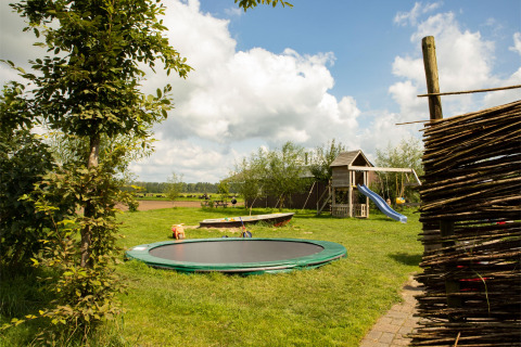Parque infantil con trampolín, tobogán y césped en Feather Down Hoeve de Betuwe, Gelderland, Países Bajos.