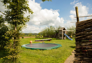 Parco giochi con tappeto elastico, scivolo e prato al Feather Down Hoeve de Betuwe, Gelderland, Paesi Bassi.