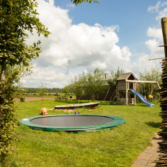 Parque infantil con trampolín, tobogán y césped en Feather Down Hoeve de Betuwe, Gelderland, Países Bajos.