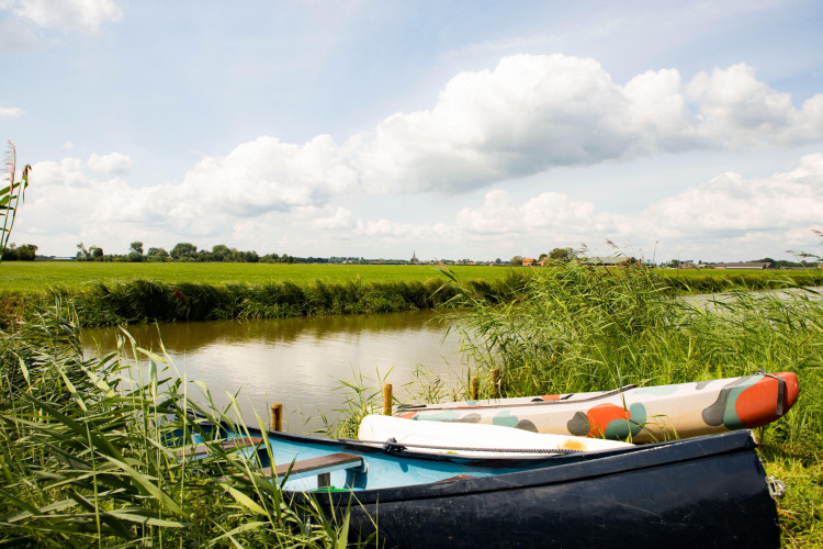 Zwei Boote liegen am grasbewachsenen Ufer eines Kanals bei Dreumel, Gelderland, Niederlande, unter bewölktem Himmel.