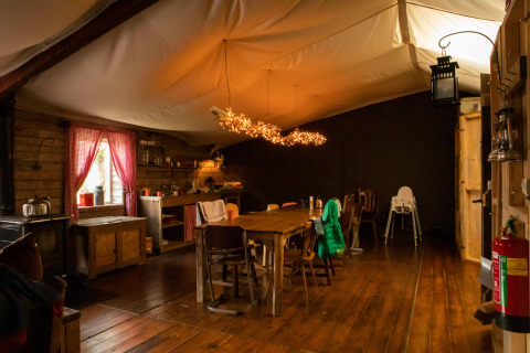 Interior acogedor de cabaña de madera con mesa de comedor grande y luces decorativas en Gelderland, Países Bajos.