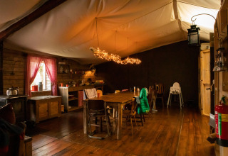 Interior acogedor de cabaña de madera con mesa de comedor grande y luces decorativas en Gelderland, Países Bajos.