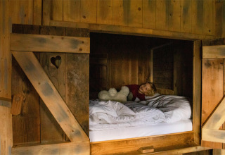 Ein Kind liegt in einer gemütlichen Holzhütte bei Feather Down Hoeve de Betuwe im Gelderland, Niederlande.