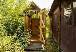 Douche extérieure près d'une tente, entourée de verdure, au Feather Down Hoeve de Betuwe aux Pays-Bas.