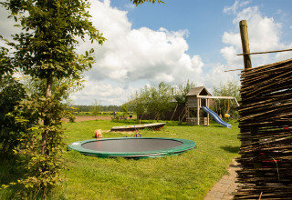 Legeplads med trampolin, rutsjebane og gynger i grønne omgivelser på feriepark i Gelderland, Holland.