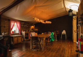 Interno accogliente di una baita con tavolo in legno, luci calde e cucina rustica in Gelderland.