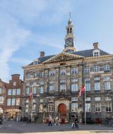 Ayuntamiento histórico en Dreumel, Gelderland, Países Bajos, con arquitectura clásica y transeúntes alrededor.