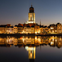 Vue du soir de Deventer, Overijssel, Pays-Bas, bâtiments illuminés se reflétant sur l'eau paisible.