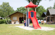 Niños juegan en un tobogán rojo junto a tiendas safari en el Camping 't Veld en los Países Bajos.