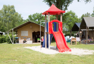 Niños juegan en un tobogán rojo junto a tiendas safari en el Camping 't Veld en los Países Bajos.