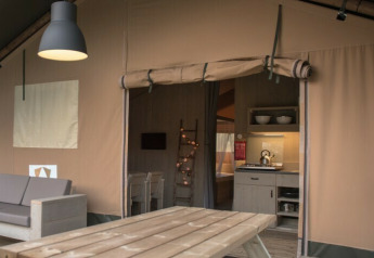 Tienda safari Comfort en Camping 't Veld, Países Bajos, con mobiliario moderno y cocina acogedora.