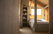 Camera da letto della tenda Safari Comfort con letto matrimoniale e scaffali al Camping ‘t Veld nei Paesi Bassi.
