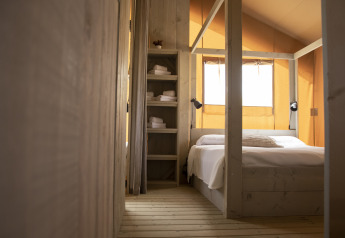 Camera da letto della tenda Safari Comfort con letto matrimoniale e scaffali al Camping ‘t Veld nei Paesi Bassi.