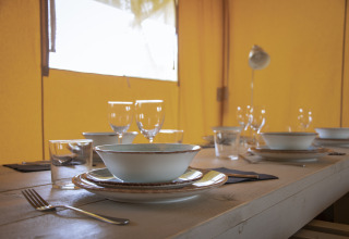 Gedekte tafel met servies en glazen in een Comfort Safari tent op Camping 't Veld, Nederland.