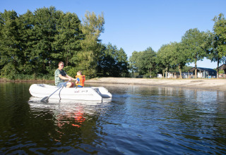 Un homme et un enfant avec gilet de sauvetage profitent d’une balade en barque à Camping 't Veld, Pays-Bas.