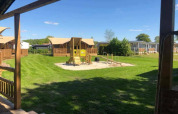 Safari telt de luxe ved Camping 't Veld i Nederlandene, viser legeplads og hytter under blå himmel.