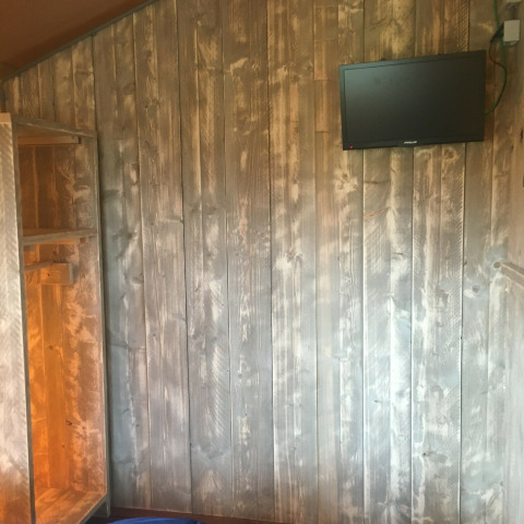 Vista interior de la tienda Safari de lujo en Camping 't Veld, Países Bajos, con pared de madera y televisor.