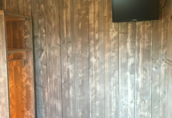 Interno della tenda Safari de luxe al Camping 't Veld nei Paesi Bassi, con parete in legno e TV.