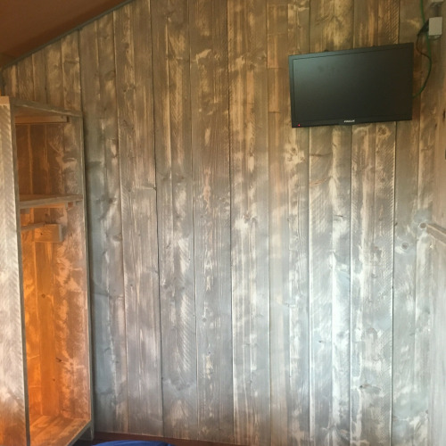 Interior view of Safari tent de luxe at Camping 't Veld in the Netherlands, featuring wood panel wall and TV.