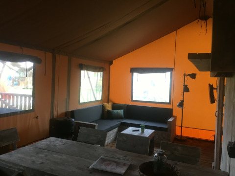 Interior de una tienda safari de lujo en Camping 't Veld, Países Bajos, con muebles rústicos de madera.