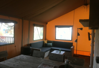 Interior de una tienda safari de lujo en Camping 't Veld, Países Bajos, con muebles rústicos de madera.