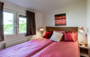 Dormitorio acogedor con ropa de cama rosa en Rialto Wellness (Spa), Recreatiepark Beekbergen, Países Bajos.