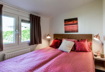 Chambre confortable avec literie rose et coussins au Rialto Wellness (Spa), Recreatiepark Beekbergen, Pays-Bas.