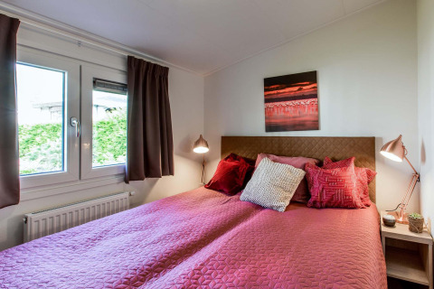 Dormitorio acogedor con ropa de cama rosa en Rialto Wellness (Spa), Recreatiepark Beekbergen, Países Bajos.