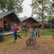 Bambini giocano davanti a tende safari al Camping 't Veld nei Paesi Bassi, adulti osservano e biciclette.