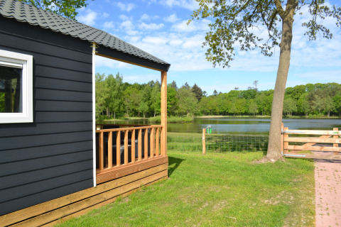 Vista dalla Beach House al Camping 't Veld nei Paesi Bassi, con stagno, alberi e prato verde.