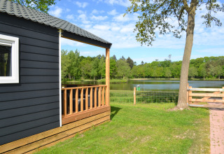 Vista dalla Beach House al Camping 't Veld nei Paesi Bassi, con stagno, alberi e prato verde.