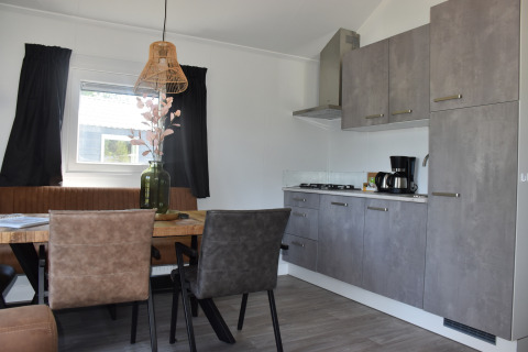 Cucina moderna e zona pranzo al Beach House lodge di Camping 't Veld, Paesi Bassi, con arredi eleganti.
