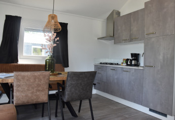 Cucina moderna e zona pranzo al Beach House lodge di Camping 't Veld, Paesi Bassi, con arredi eleganti.