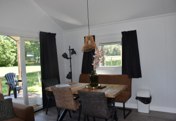 Interno accogliente di Beach House al Camping 't Veld nei Paesi Bassi, zona pranzo e vista sul giardino.