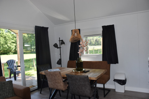 Interno accogliente di Beach House al Camping 't Veld nei Paesi Bassi, zona pranzo e vista sul giardino.