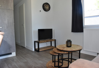 Sala de estar en Beach house lodge, Camping 't Veld, Países Bajos, con mesas de madera y decoración moderna.