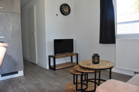 Woonkamer in Beach house lodge, Camping 't Veld, Nederland, met houten tafels en moderne inrichting.