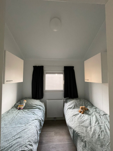 Due letti singoli con giocattoli in una camera luminosa della lodge Beach house al Camping 't Veld, Paesi Bassi.
