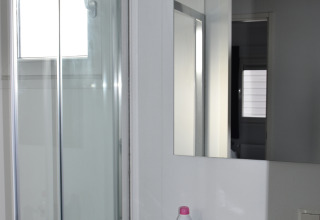 Badkamer met douche, spiegel en lavabo in Beach house op Camping 't Veld, Nederland, daglicht.