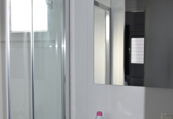 Bathroom with shower, mirror, and sink in a Beach house at Camping 't Veld, Netherlands, daylight view.