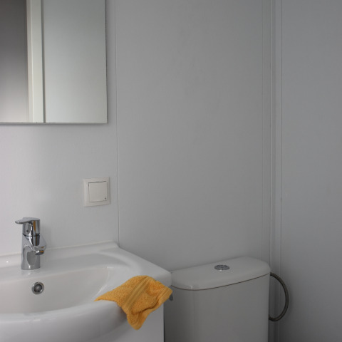 Bagno al Beach house, Camping 't Veld nei Paesi Bassi, con lavabo, specchio e asciugamano giallo.