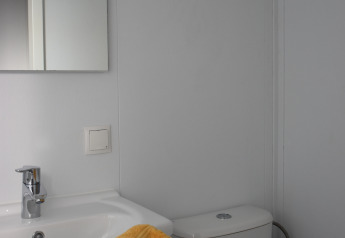 Bagno al Beach house, Camping 't Veld nei Paesi Bassi, con lavabo, specchio e asciugamano giallo.