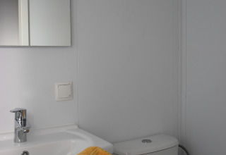 Bagno al Beach house, Camping 't Veld nei Paesi Bassi, con lavabo, specchio e asciugamano giallo.