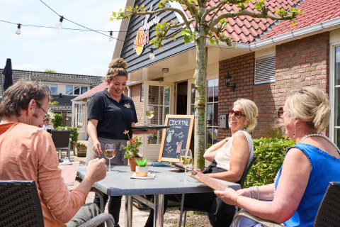 Terraza al aire libre en Beach house, Camping 't Veld, Países Bajos, personas disfrutan comida y bebida.