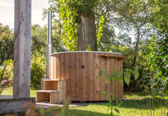Holz-Whirlpool im Freien neben einer kleinen Hütte im grünen Vakantiepark Hölte in den Niederlanden.