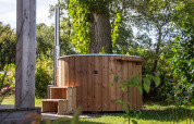 Udendørs træhot tub ved siden af et lille hus i grønne omgivelser i Vakantiepark Hölte, Holland.