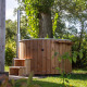Wooden outdoor hot tub next to a tiny cabin surrounded by greenery at Vakantiepark Hölte, Netherlands.